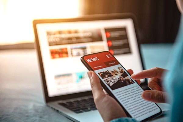 Public Relations & Medienarbeit News auf Smartphone vor Laptop – PR, Medienarbeit und digitale Reichweite